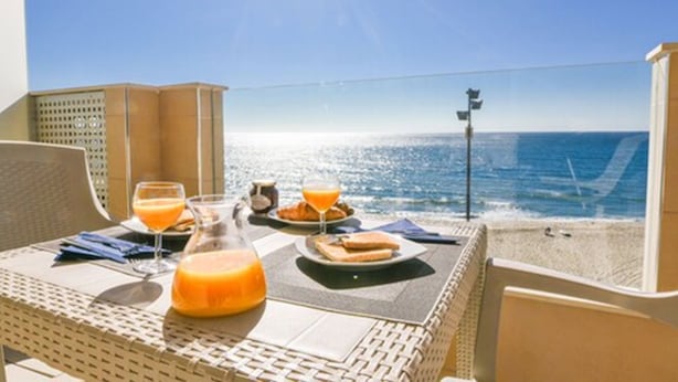A table with breakfast items and a glass of orange juice on a balcony overlooking the sea. - Apartamentos Vegasol Playa A.T. (Fuengirola)