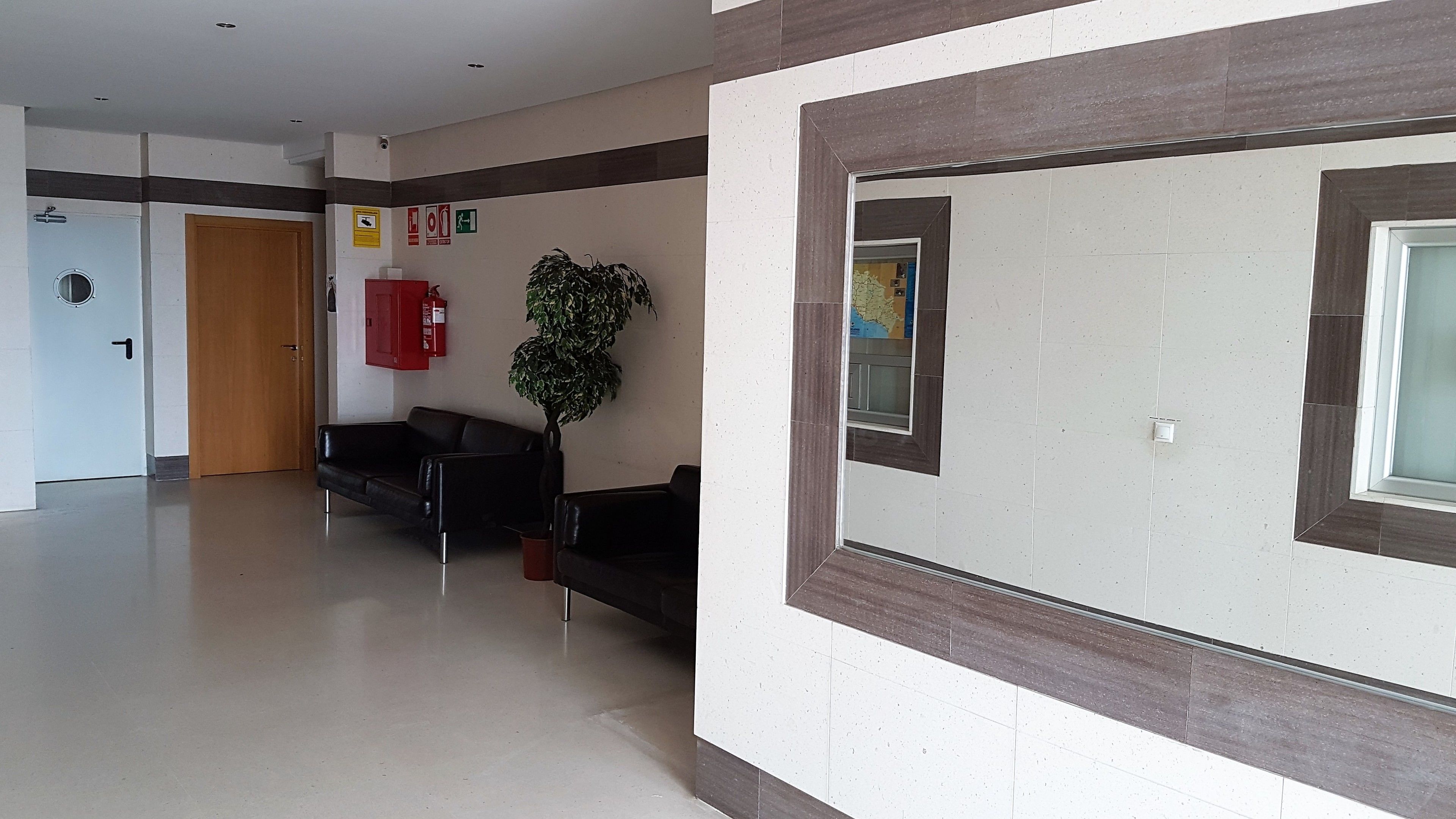 A hallway with a reception desk, a fire extinguisher, and a map on the wall.