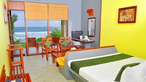 A hotel room with a bed, desk, chairs, and a view of the ocean. - Club Koggala Village (Koggala)
