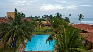 A swimming pool surrounded by palm trees and a beach view. - Club Koggala Village (Koggala)