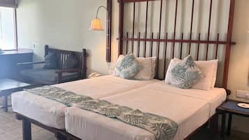 Una cama doble con cabecera de madera, dos lámparas de noche y una mesita con un teléfono.
