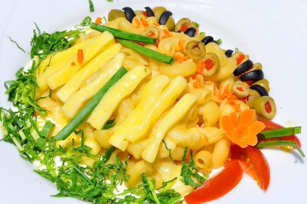 Un plato de pasta con verduras y una decoración floral.