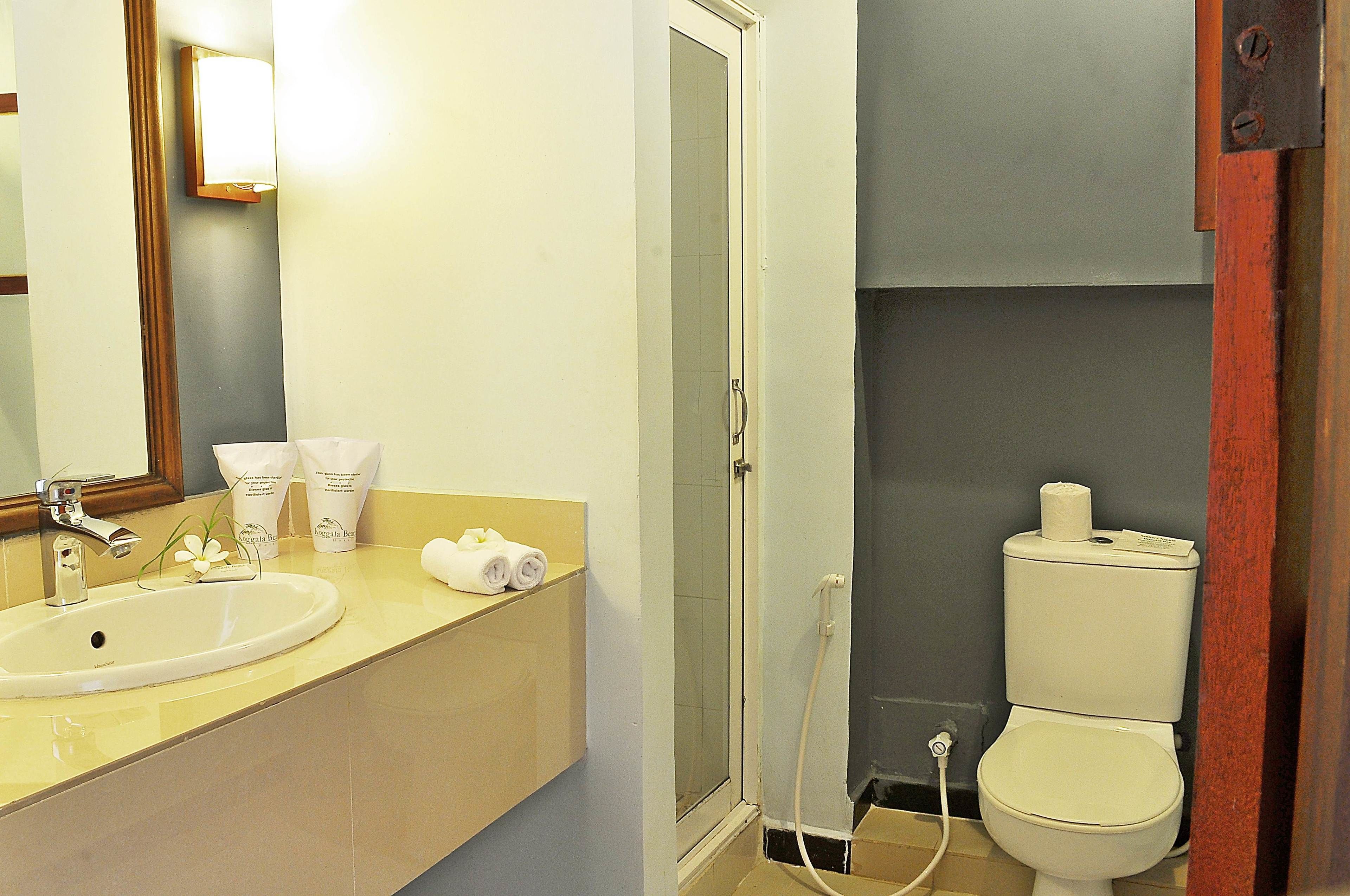 A bathroom with a sink, mirror, toilet, and shower.