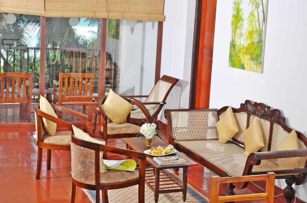 A room with wooden furniture, including chairs and a sofa, arranged around a central table with a vase of flowers.
