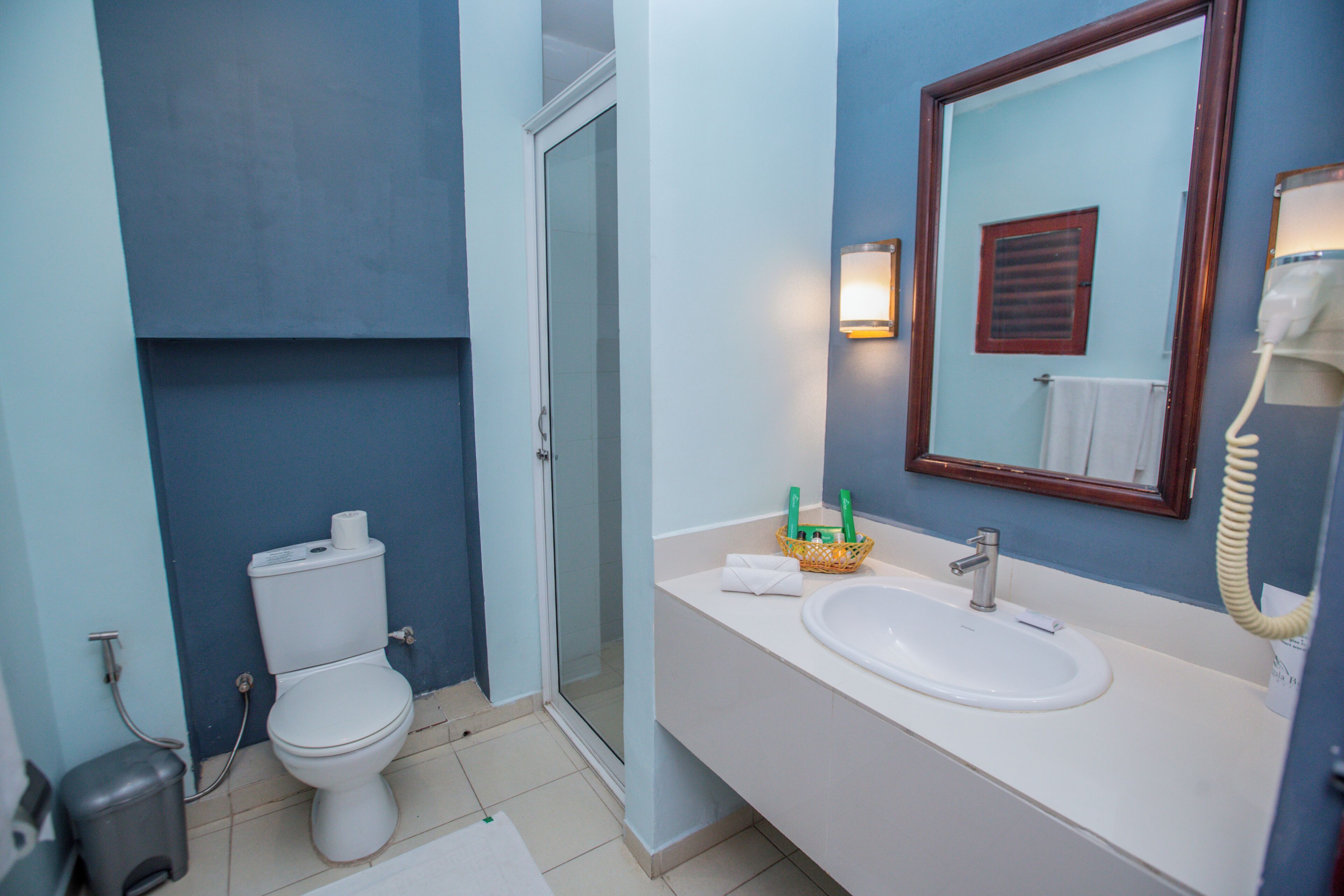 Une salle de bain équipée de toilettes, d’un lavabo, d’un miroir et d’une douche.