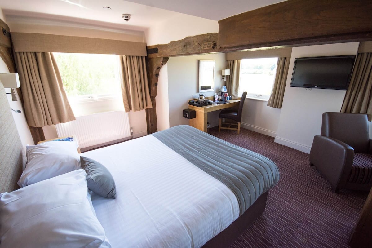 Une chambre d’hôtel avec un grand lit, un bureau, une chaise et un téléviseur.