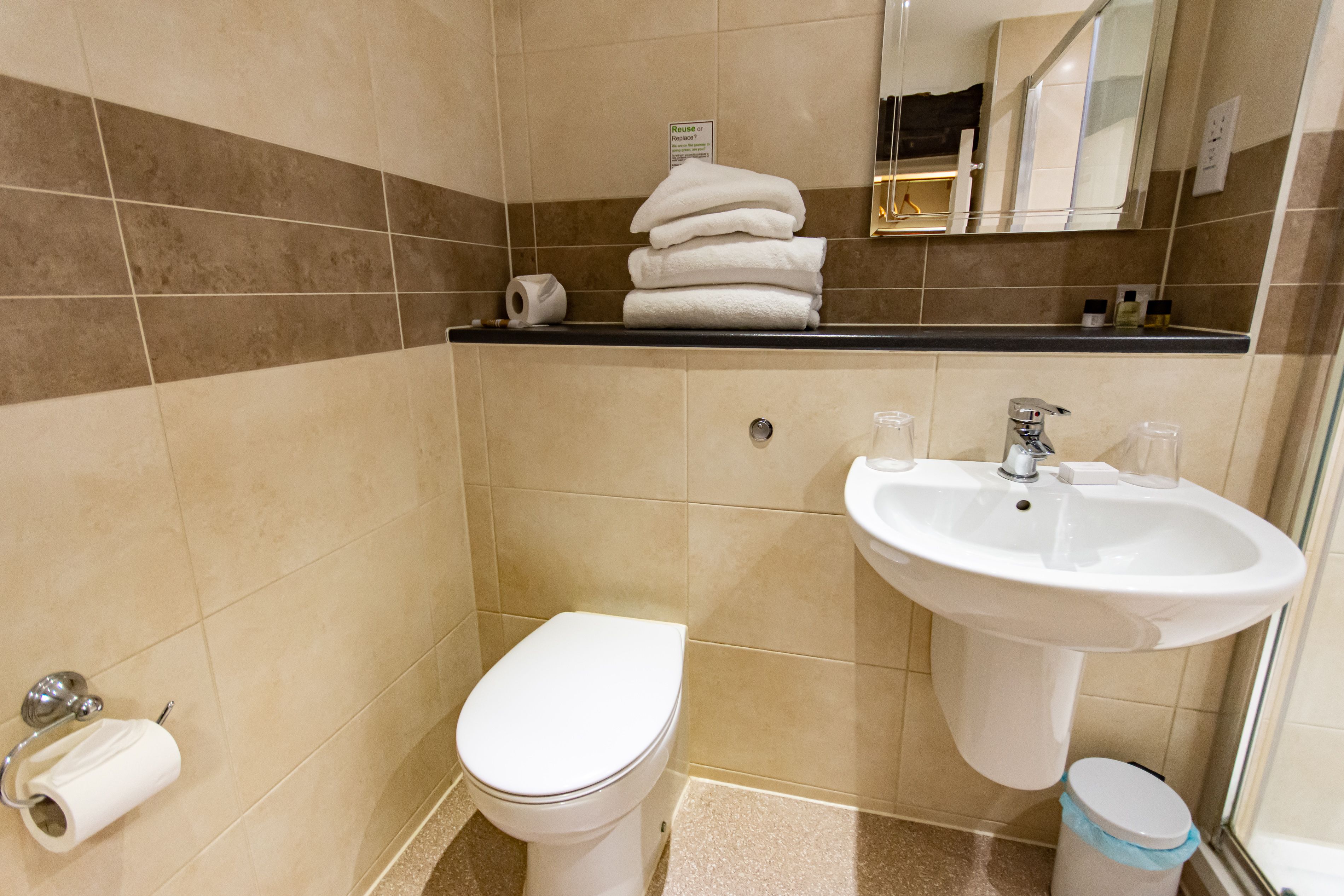Un baño con inodoro, lavamanos y una pila de toallas.