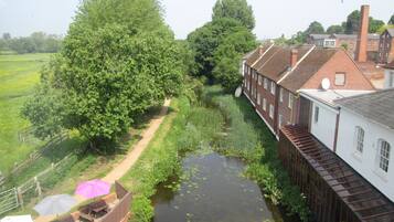 A narrow canal with a wooden walkway, surrounded by lush greenery and traditional brick buildings.