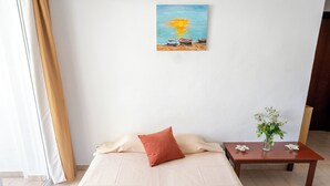 A hotel room with a bed, a bedside table, a painting, and an air conditioning unit. - Apartamentos Cala LLonga Playa Ibiza (Santa Eulalia del Rio)