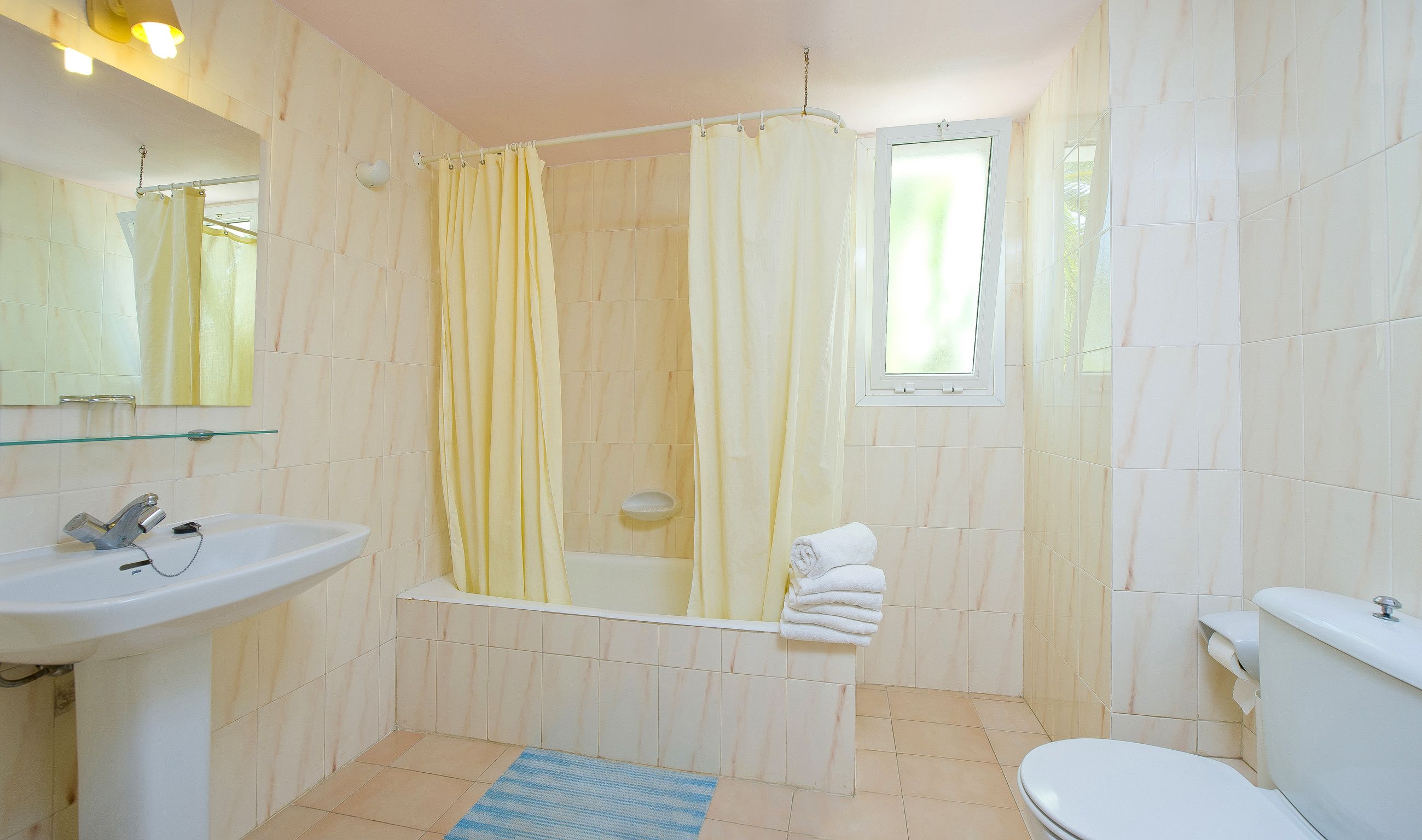 Un baño con bañera, lavabo, inodoro y ventana.