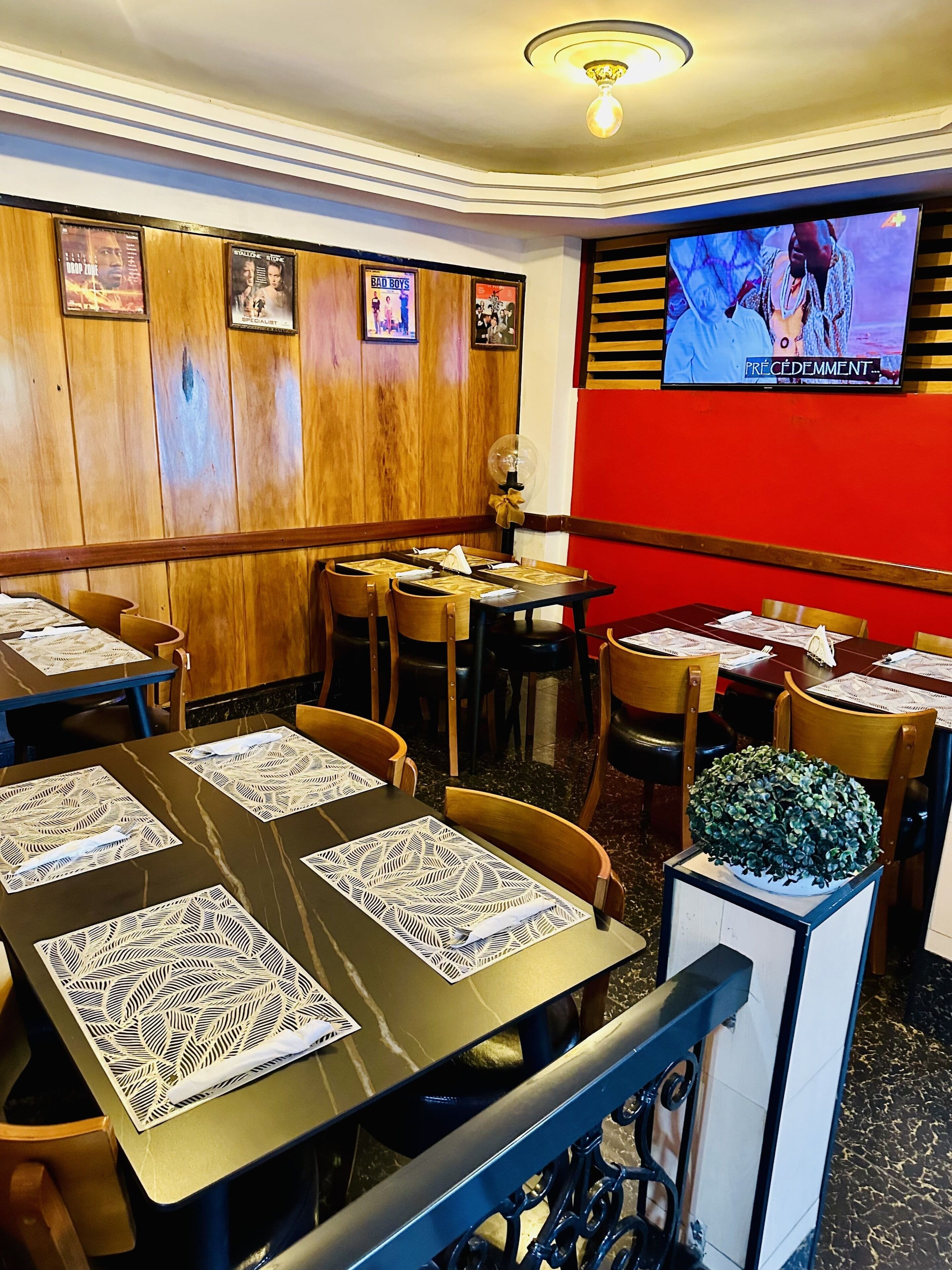 Interior de restaurante con paredes de paneles de madera, varias mesas con manteles individuales y una pantalla de televisión mostrando un programa.