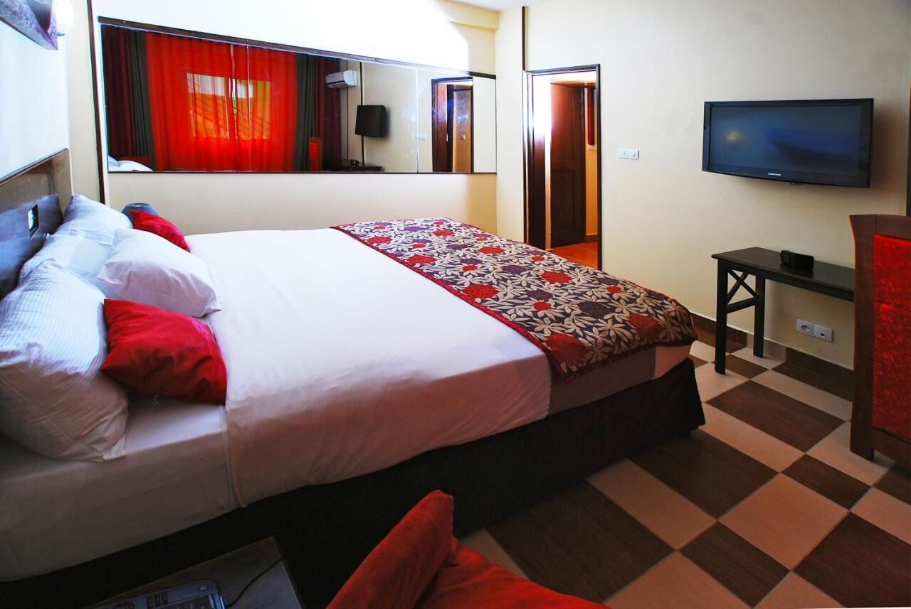 Une chambre d’hôtel avec un grand lit, une télévision, un bureau et un miroir.