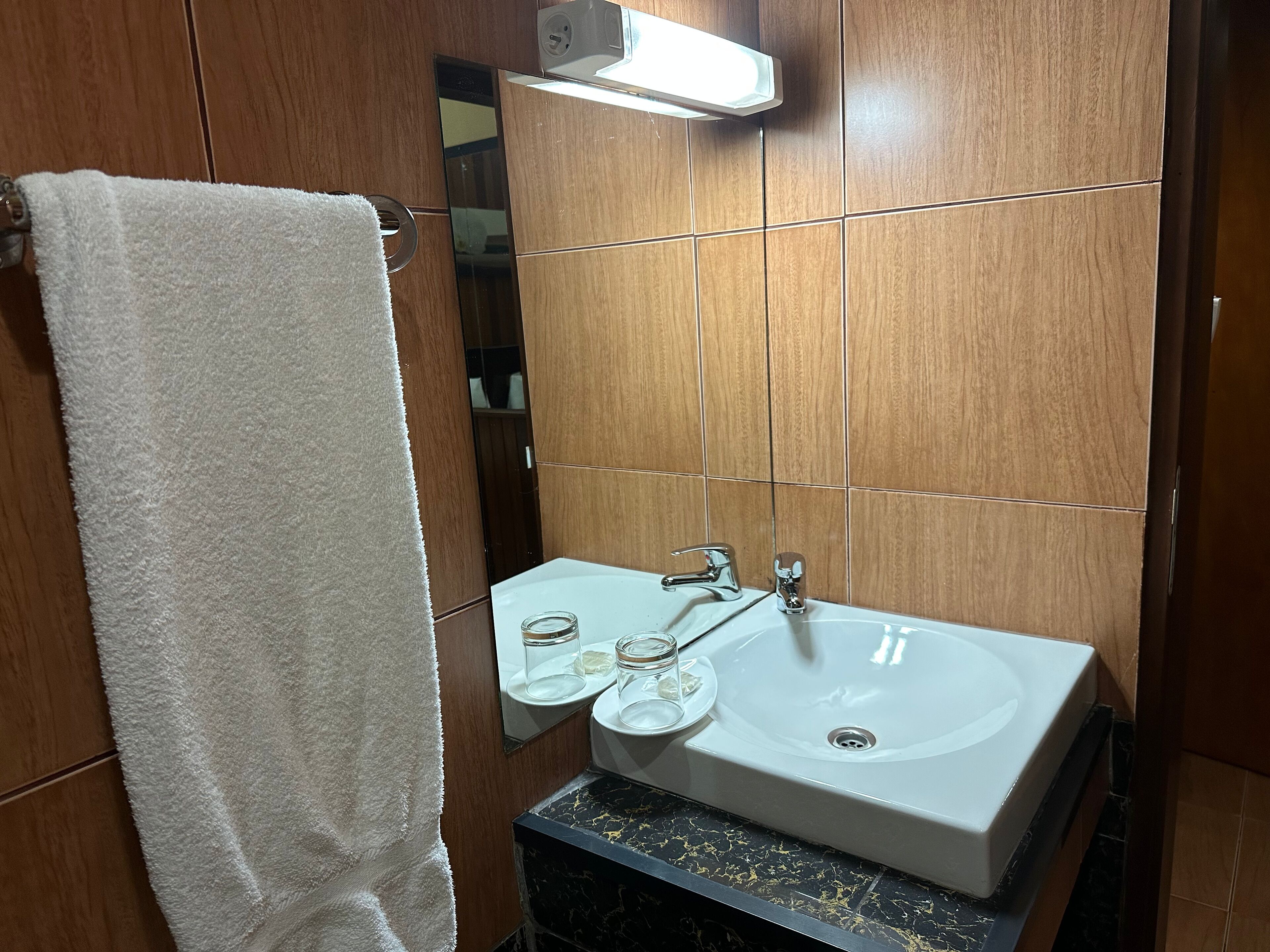A bathroom with a white sink, a mirror, and a towel hanging on a rack.