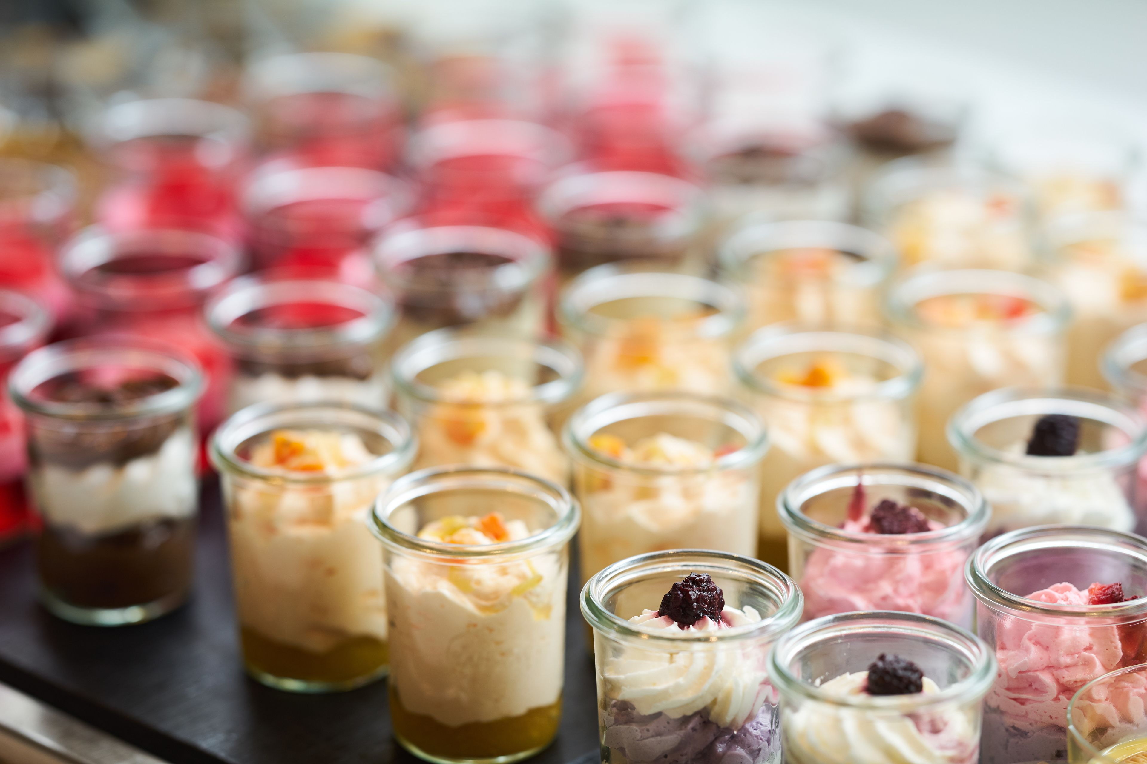 A variety of desserts in small glass jars, arranged on a tray.