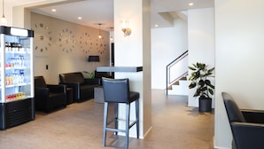 A lobby with seating, a refreshment machine, a wall clock, and a staircase. - Fosshotel Westfjords (Vesturbyggð)