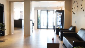 A modern lobby with a reception desk, seating area, and a large glass door leading outside. - Fosshotel Westfjords (Vesturbyggð)