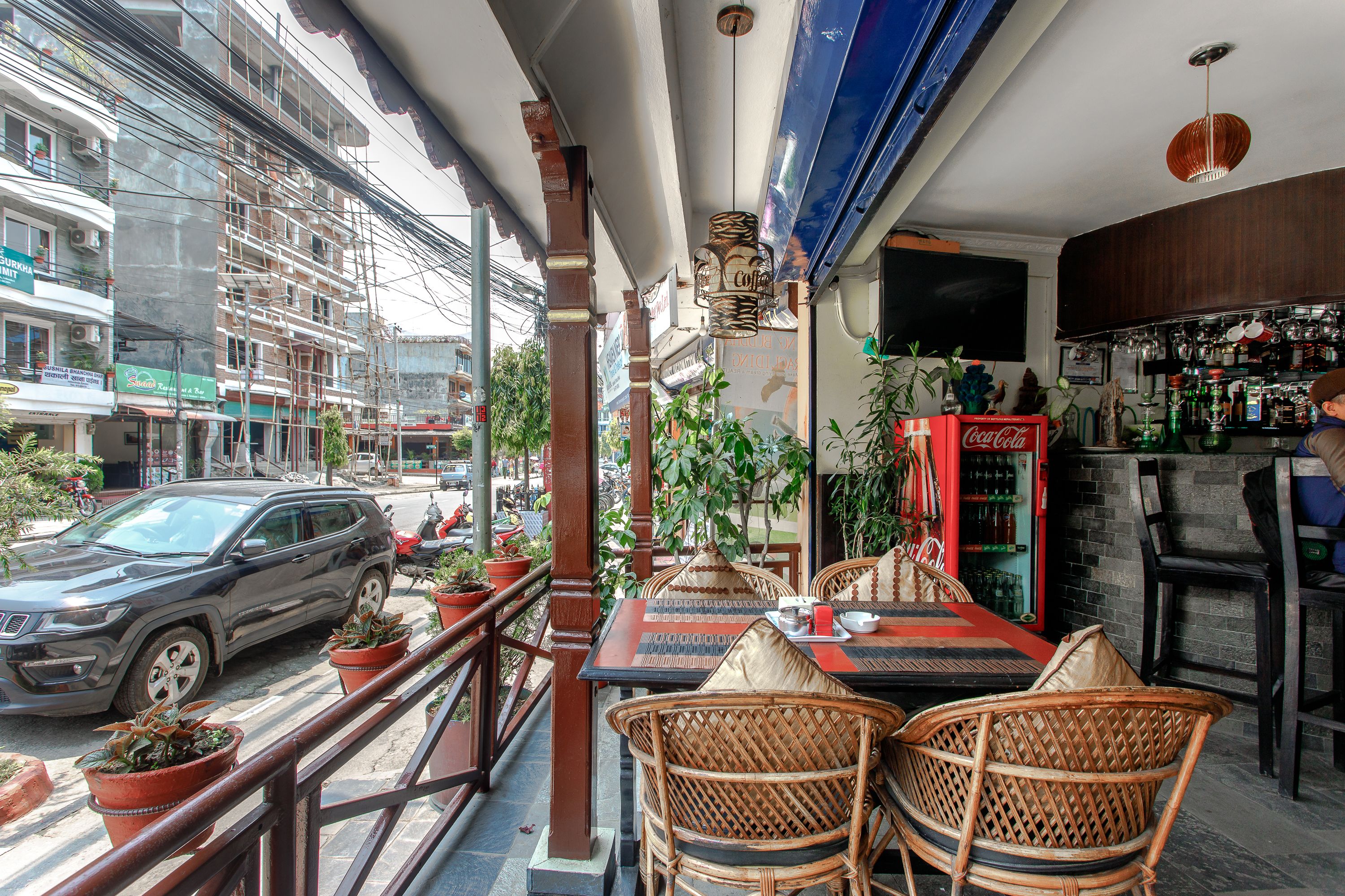 Un restaurante con terraza, un refrigerador de Coca-Cola y vistas a la calle.