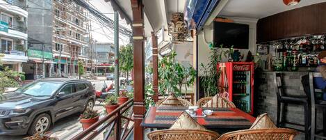 Un restaurante con terraza, un refrigerador de Coca-Cola y vistas a la calle.