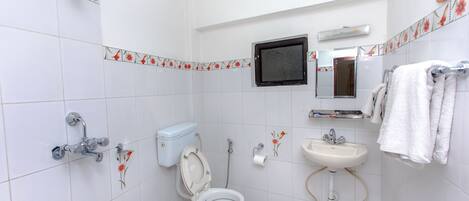 A bathroom with a toilet, sink, shower, and a mirror.