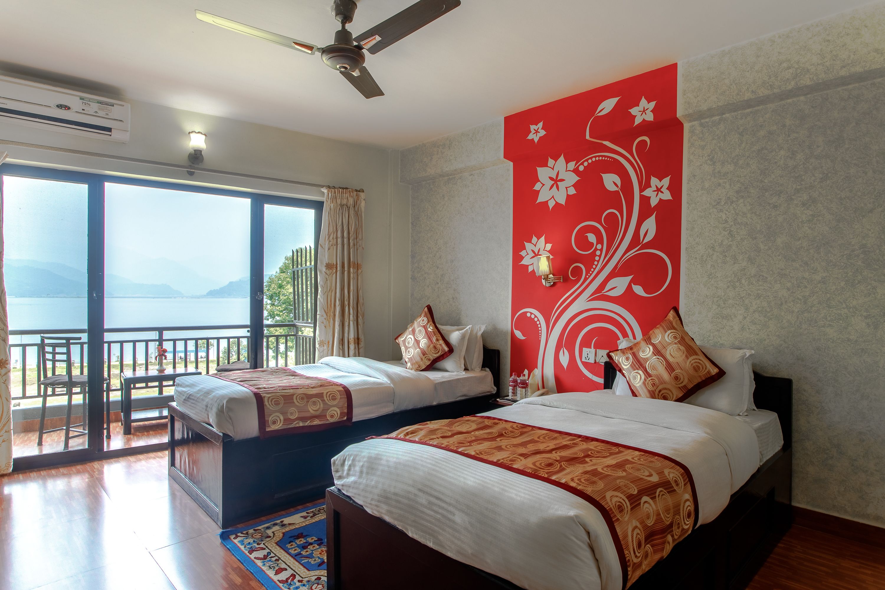 A hotel room with two beds, a balcony, and a view of the mountains.
