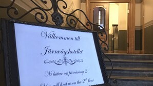 Un cartel en el vestíbulo de un hotel con un mensaje en idioma extranjero, que indica la ubicación de la recepción en el segundo piso.