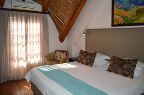 A bedroom with a large bed, a chair, and a painting on the wall.