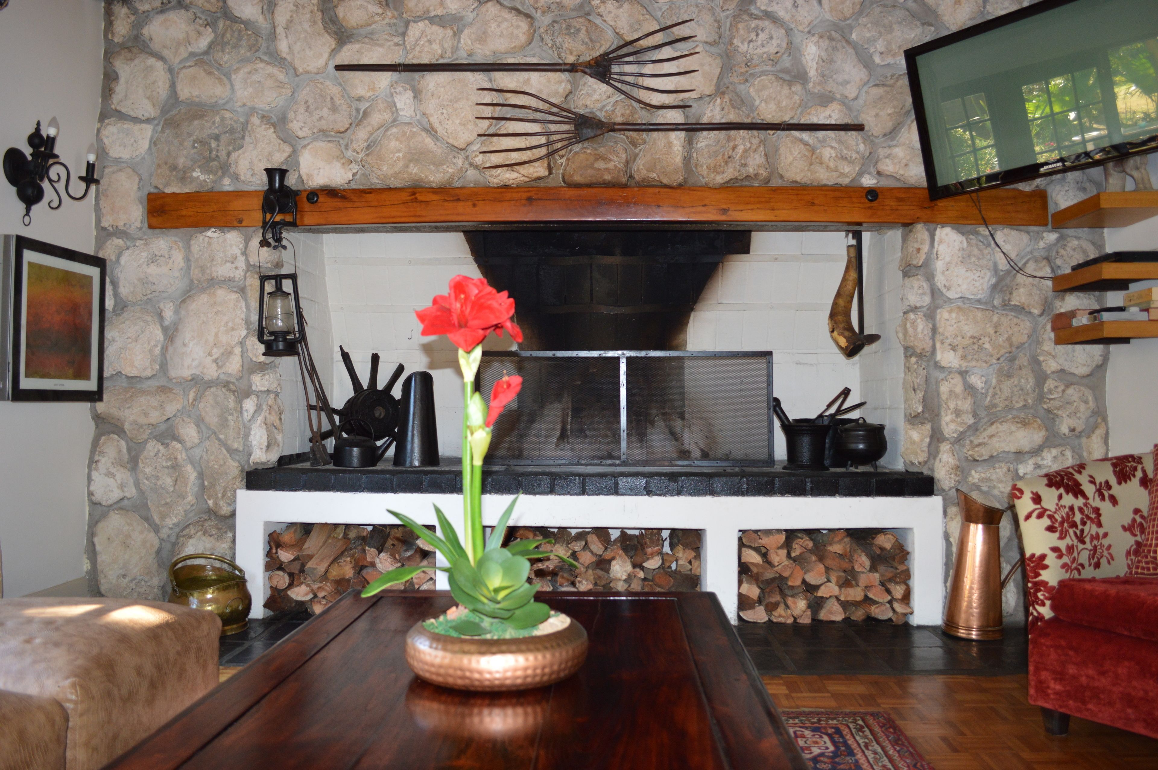 A stone wall, a fireplace, a wooden bench, and a red chair in a living room.