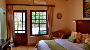 Un dormitorio con cama, una silla, una mesa y un ventanal con cortinas.
