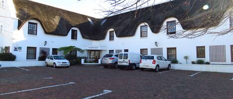 A building with a unique curved roof, a parking area with several cars, and a sign that reads "OAKURST".