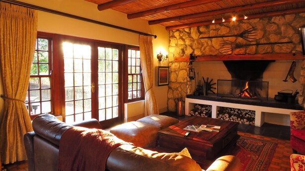 Una sala de estar acogedora con chimenea de piedra, sofá de cuero y una mesa de centro.