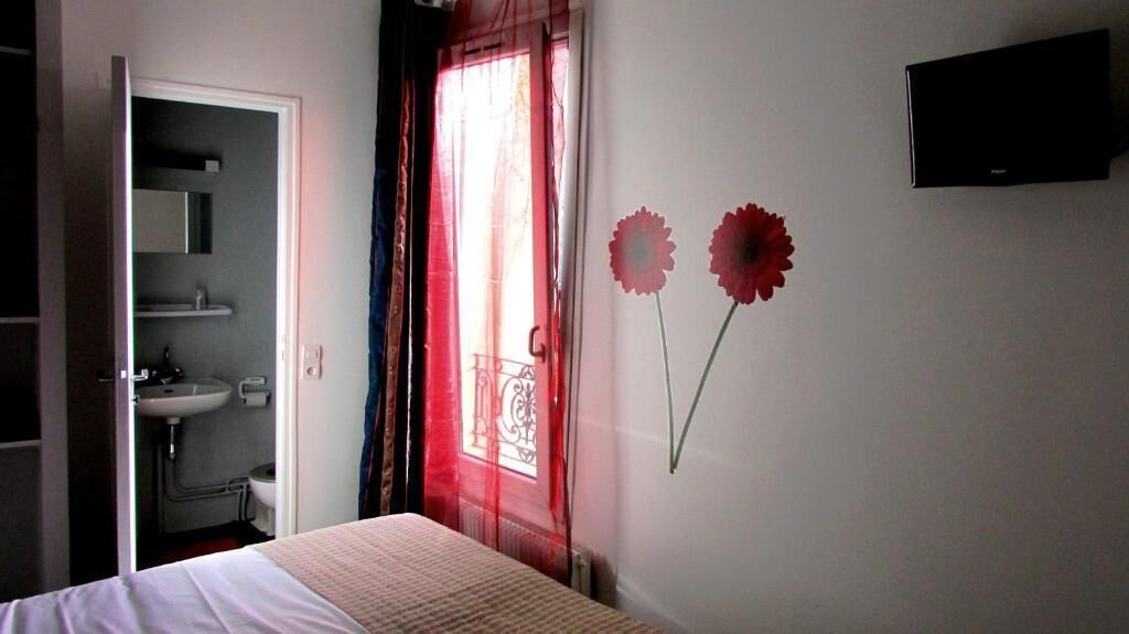 Une chambre avec un lit, une salle de bain avec un lavabo et un téléviseur fixé au mur.