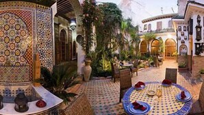 A courtyard with a round table, chairs, and a decorative fountain. - Riad Meknès (Meknes)