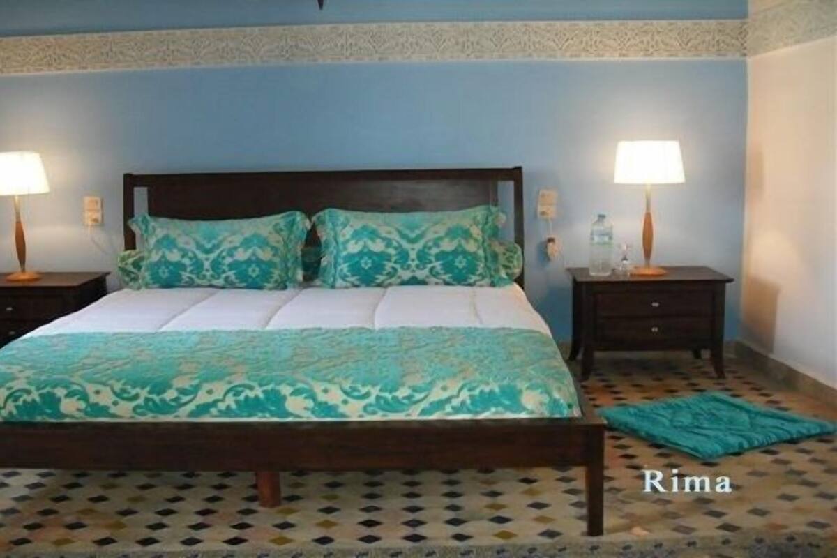 A bedroom with a bed, two bedside tables, and two lamps.