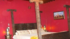 A traditional room with a four-poster bed, red walls, and a framed picture on the wall. - Riad Meknès (Meknes)