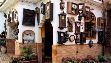 A building with multiple clocks on the exterior walls, a door with a decorative arch, and potted plants.