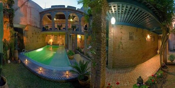 A pool area with a surrounding garden and a covered seating area. - Riad Meknès (Meknes)