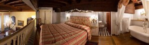 Un dormitorio con una cama grande, una araña, una escalera de madera y un baño con bañera.