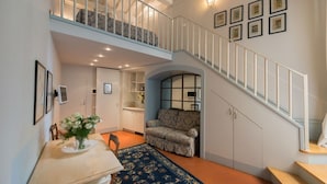 A spacious living area with a high ceiling, a staircase, and a dining area with a table and chairs. - Corte dei Neri (Florence)