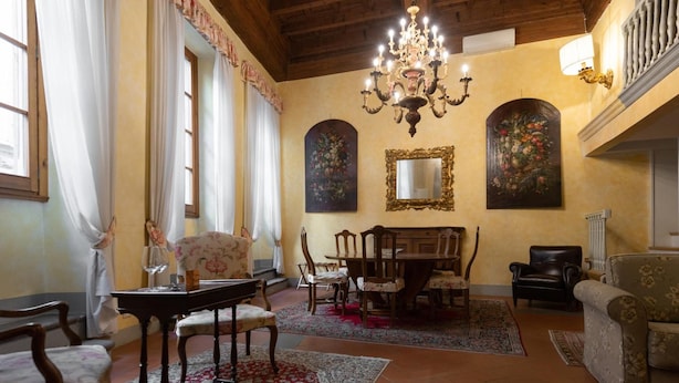 A traditional dining room with a chandelier, wooden furniture, and floral wall art. - Corte dei Neri (Florence)
