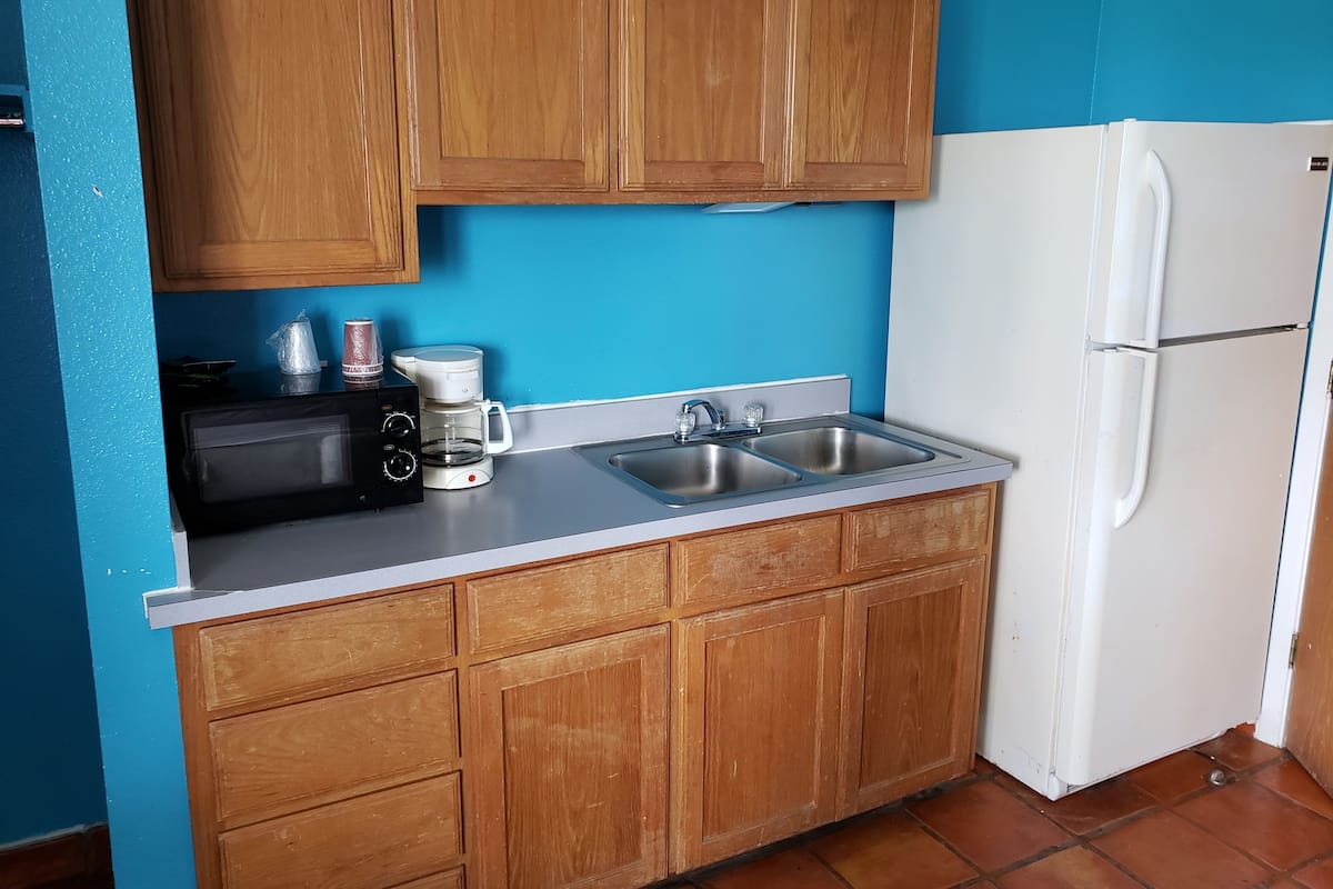 A kitchen with wooden cabinets, a microwave, a coffee maker, and a white refrigerator.