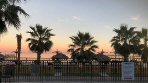 A swimming pool with a view of the sunset and palm trees. - Hunt's Castle (Rockport)