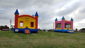 Two inflatable bounce houses in a grassy field. - Hunt's Castle (Rockport)