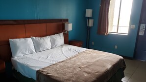 A hotel room with a bed, a nightstand, a lamp, and a window with curtains. - Hunt's Castle (Rockport)