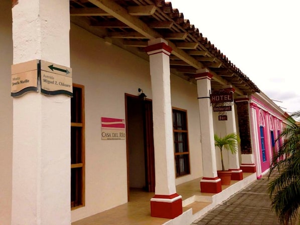 A hotel with a traditional architectural style, featuring a tiled roof and a sign indicating it is a restaurant and bar.