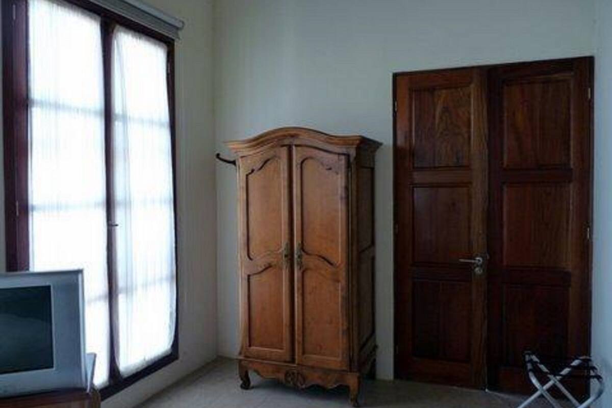 Une pièce avec une grande fenêtre, un meuble en bois, une porte et une chaise.