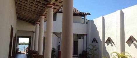 Un espacio al aire libre cubierto con columnas, plantas en macetas y vista al mar.