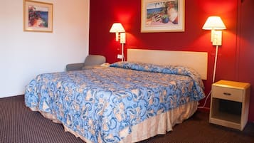 Une chambre d’hôtel avec un grand lit, deux lampes de chevet, une chaise et deux tableaux encadrés accrochés au mur.