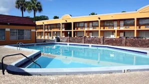 A motel with a swimming pool, multiple balconies, and palm trees in the background. - Scottish Inn Jacksonville Downtown (Jacksonville)
