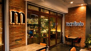 An indoor cafe with brick walls, a visible 'manifesto' sign, and a no smoking/cigarette sign.