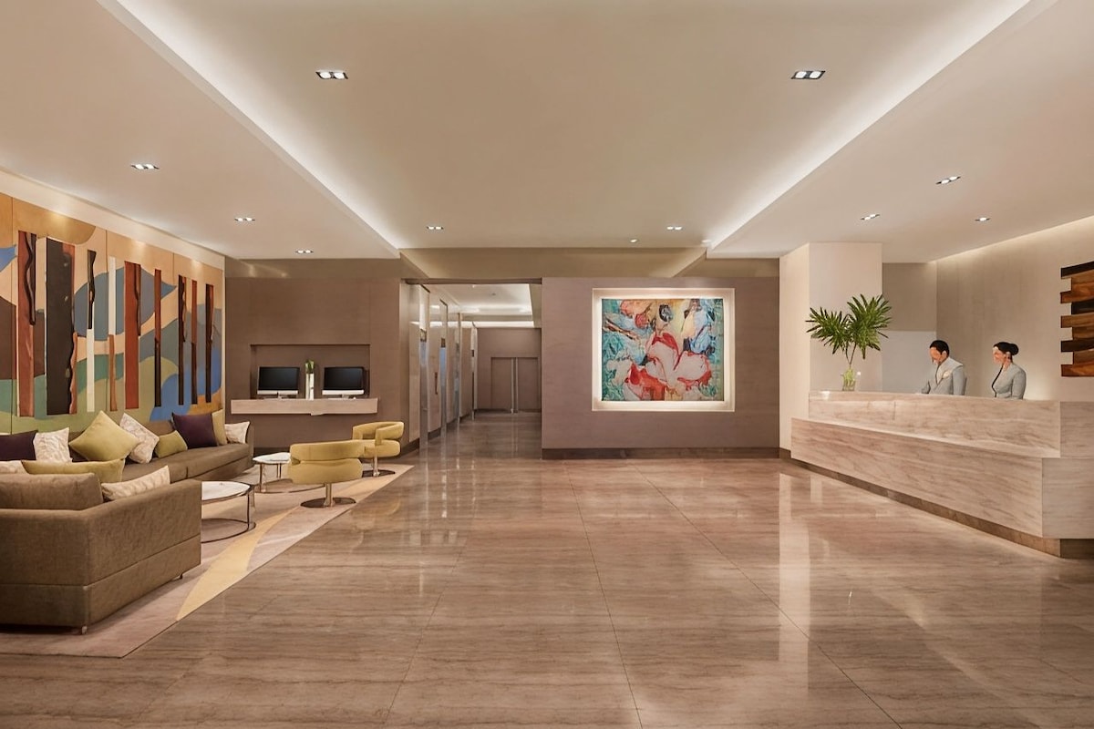 A modern lobby with a reception desk, seating area, and artwork.